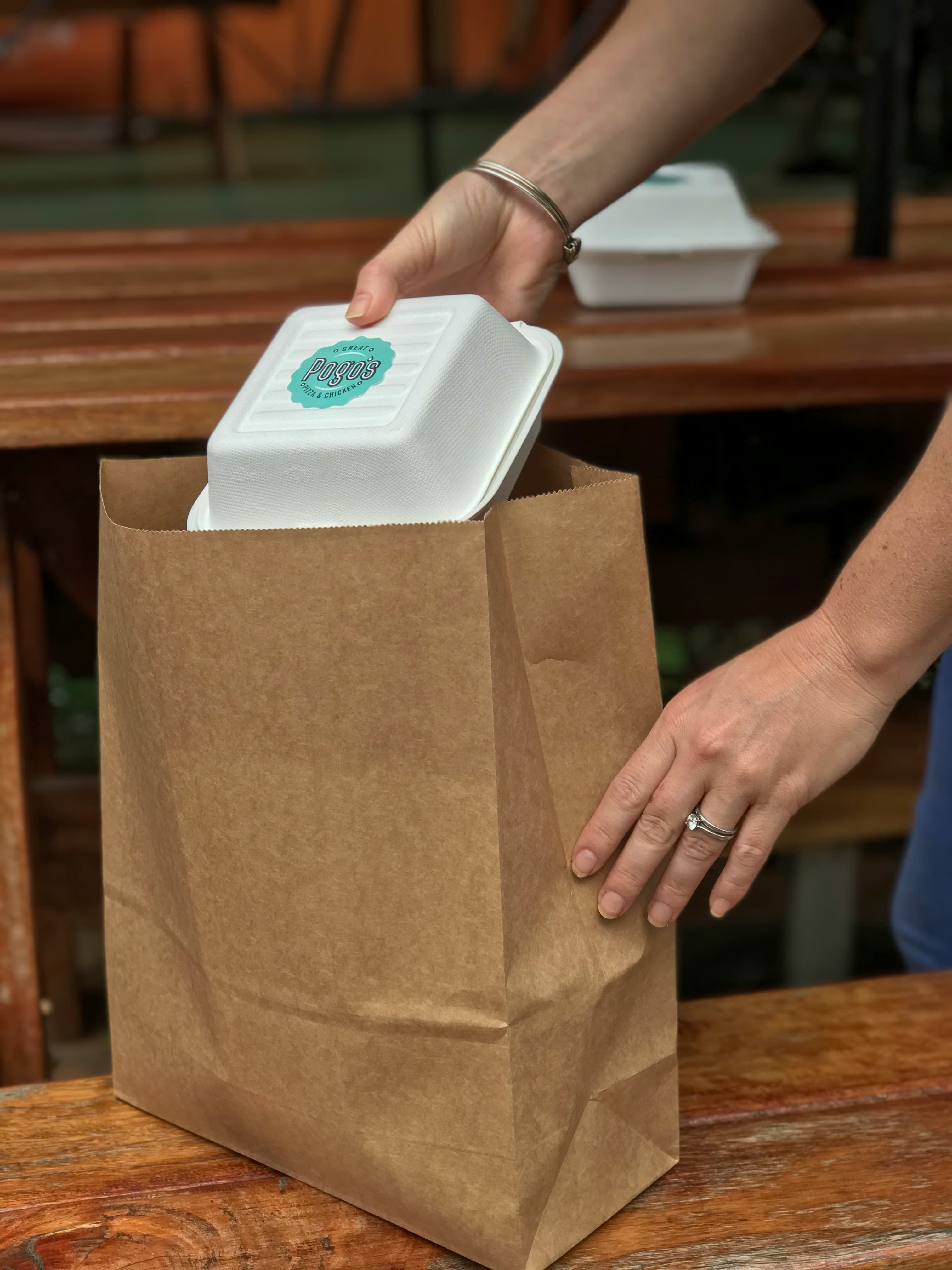 Person holding a brown paper bag — a meal being picked up